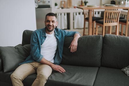 Handsome bearded man sitting on comfortable couch at homeの写真素材