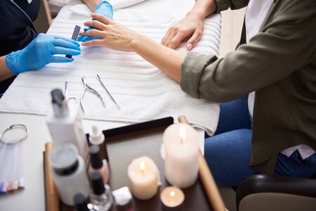 Manicure master filing and shaping lady nails with emery boardの写真素材