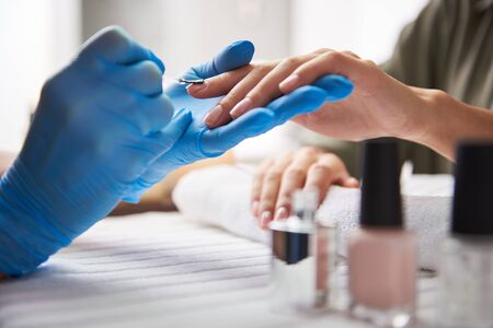 Manicurist applying clear nail polish on lady nails