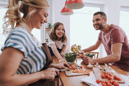 Happy family spending time together and cooking dinner at homeの写真素材
