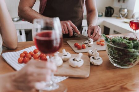 Man in apron cutting mushrooms with knifeの写真素材