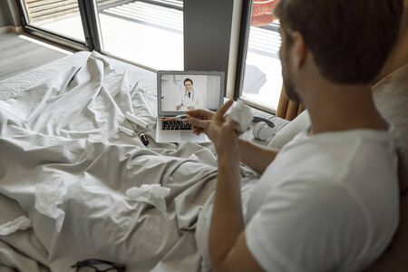 Young man telling his doctor his body temperatureの写真素材