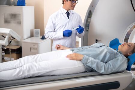 Doctor holding venflon catheter and looking at patientの写真素材