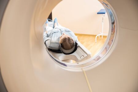 Young woman lying on CT scanner table at hospitalの写真素材