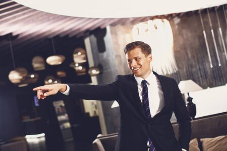 Confident young man smiling and pointing to the distance