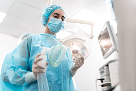 Serious anesthesiologist standing with the anesthetic mask in her handの写真素材