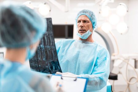 Worried male doctor looking at the x-ray results and thinkingの写真素材