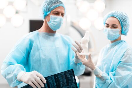 Confident doctors discussing bone model while looking at itの写真素材