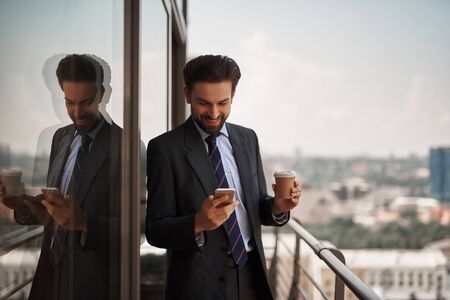 Man in office suit checking massages on phoneの写真素材