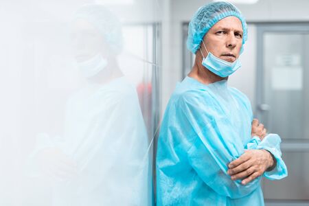 Close up of calm doctor standing near the wall and frowningの写真素材