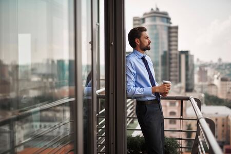 One male worker drinking coffee on office balconyの写真素材