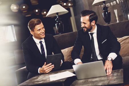 Two business partners sitting at the table and smiling while talkingの写真素材