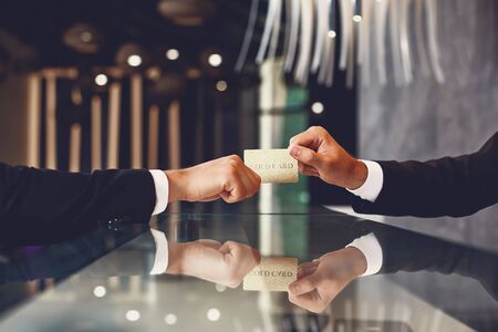 Elegant person giving the gold card to attentive receptionist
