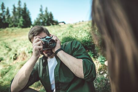 Young man taking photo of woman on green hill