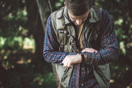 Man looking at his watch travelling in forest
