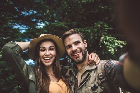 Smiling couple making selfie in green forest