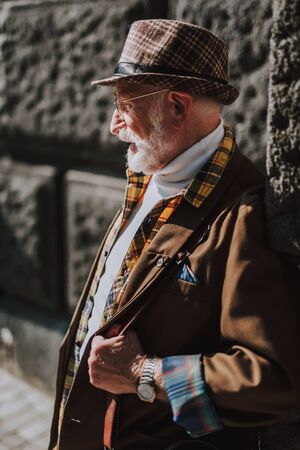 Side portrait of stylish old man leaning the wallの写真素材