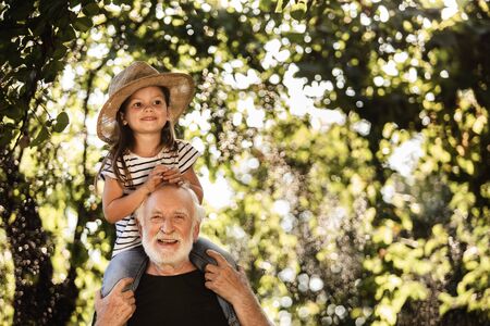 Little girl with old man having fun in gardenの写真素材