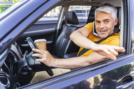 Handsome Caucasian man is talking on cellphone in car