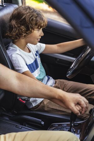 Caucasian man helping little boy to drive car