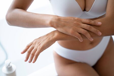 Female hands applying a moisturizing body lotion