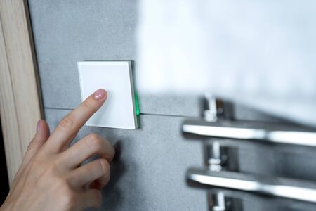 Hand turning on the light in the bathroom