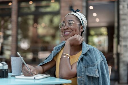 Happy woman with sketchbook drinking coffee outdoors stock photoの写真素材