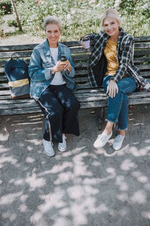 Two smiling friends sitting in a parkの写真素材