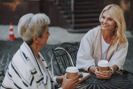 Pleased fashionable women sitting at a tableの写真素材