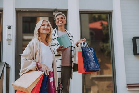 Two smiling women with bags standing outsideの写真素材