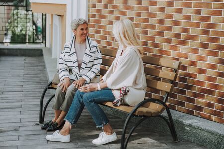 Joyful senior lady sitting next to a friendの写真素材