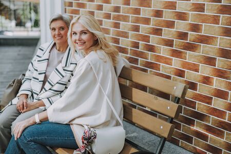 Happy friends sitting near a brick building