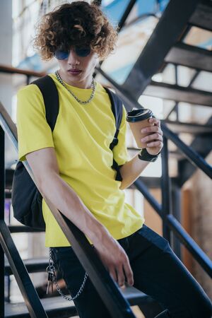 Stylish boy with hot drink on stepsの写真素材