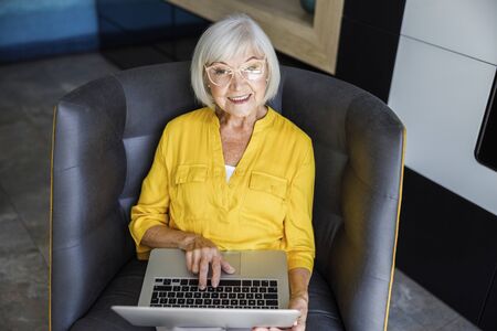 Smiling adult female is typing on laptop