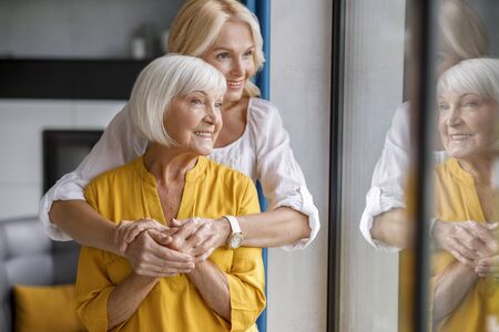 Smiling mature mother and daughter together at homeの写真素材