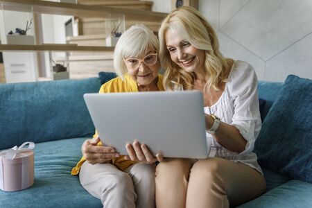 Happy ladies looking at screen at homeの写真素材