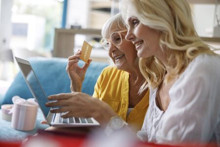 Happy mother and daughter looking at screen on laptopの写真素材
