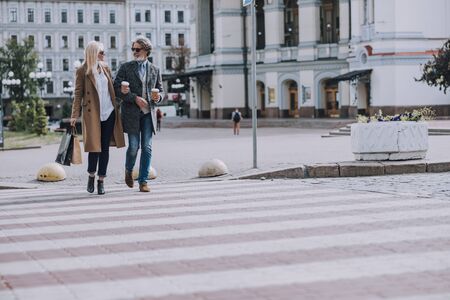 Smiling man and woman crossing the road stock photoの写真素材