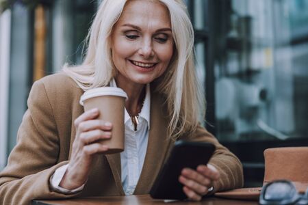 Happy mature woman is sitting in street cafeの写真素材