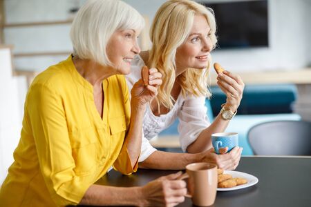 Beautiful adult women are tasting cookies at homeの写真素材
