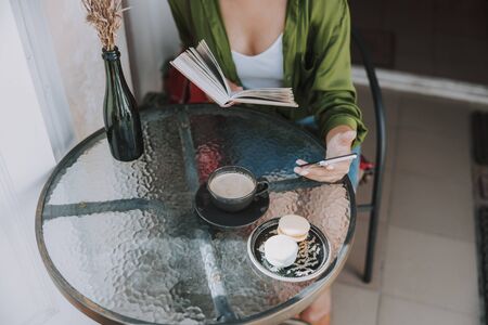 Woman with book is sitting in cafeの写真素材