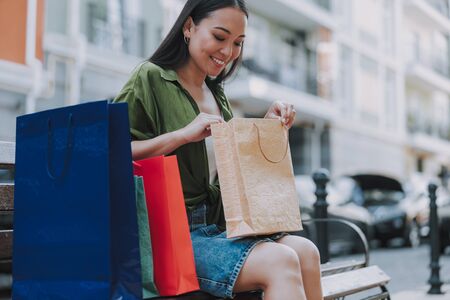 Smiling pretty lady is holding bag on benchの写真素材