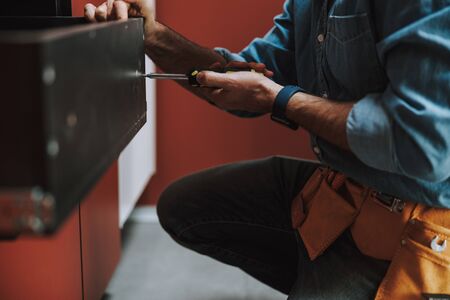 Close up of handyman fixing a drawer indoors