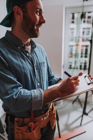 Contented construction worker smiling and writing stock photo