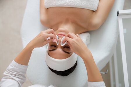 Cosmetologist cleaning young woman face stock photo