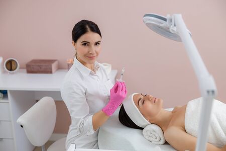 Smiling beautician holding syringe for beauty procedureの写真素材