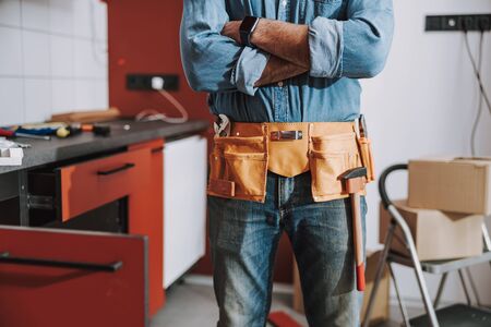 Close up of repairman standing indoors with crossed arms