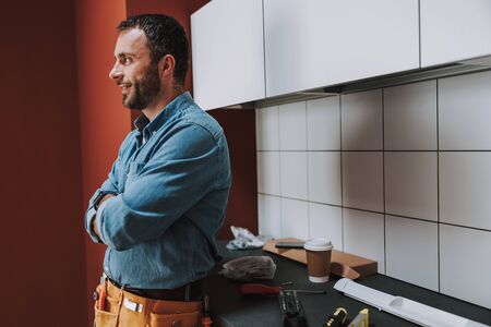 Happy young man looking away in the kitchenの写真素材