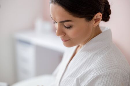 Beautiful young woman in bathrobe against blurred backgroundの写真素材
