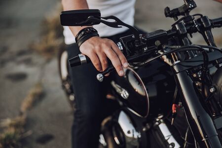 Man in t-shirt keeping hand on steering wheel of motorcycle stock photoの写真素材